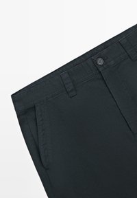Black cotton trousers with a flat front design, featuring a button closure and side pockets. Smooth texture and tailored fit.