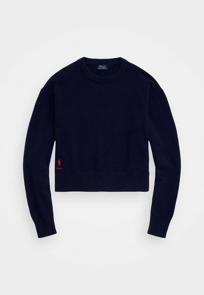 Pulover scurt, de culoare bleumarin, confecționat dintr-un material tricotat moale, având un guler și o margine cu dungi, cu un logo de polo brodat roșu în partea stângă jos.