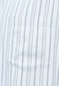 Βαμβακερό πουκάμισο με κάθετες μπλε και λευκές ρίγες, με τσέπη-μπάλωμα στο αριστερό στήθος και υφή στο ύφασμα για επιπλέον διάσταση.