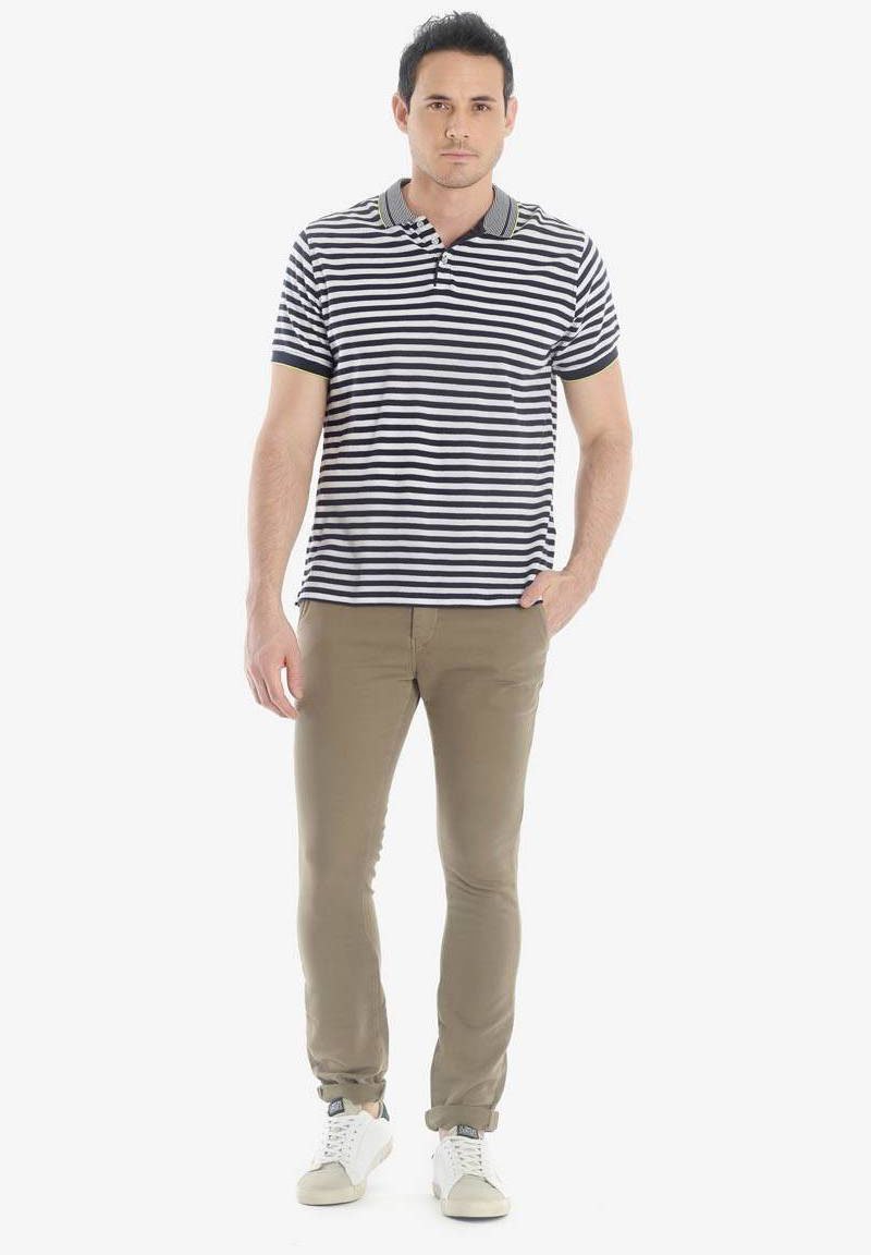 Polo a righe in blu navy e bianco, abbinato a pantaloni khaki slim-fit. L'outfit è completato da sneakers bianche.
