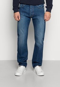 Blå raka jeans i denim med en blekt tvätt, med fem fickor, gylf med dragkedja och bärs tillsammans med vita sneakers.