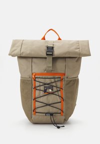 Khaki batoh s rolovacím víkem, oranžovými akcenty, boční kapsou z jemné sítě a detaily s bungee šňůrou. Obsahuje černou sponu a logo.