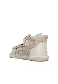 Scarpa con cinturino in velcro in suede beige con accenti iridescenti, presenta un motivo a pois, punta rotonda e suola in gomma bianca.