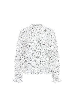 Blusa blanca con lunares negros, cuello alto, mangas largas con puños con volantes y un sutil detalle de botón en el costado. Tejido ligero.