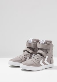Szare wysokie sneakersy wykonane z tkaniny z białymi akcentami, zapinane na sznurówki z rzepem na kostce, z teksturowaną powierzchnią.