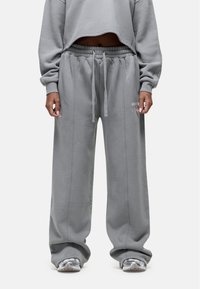 Grijze cropped sweatshirt gecombineerd met losse grijze sweatpants. De stof lijkt zacht met een geborstelde textuur. De sweatpants hebben een elastische tailleband.