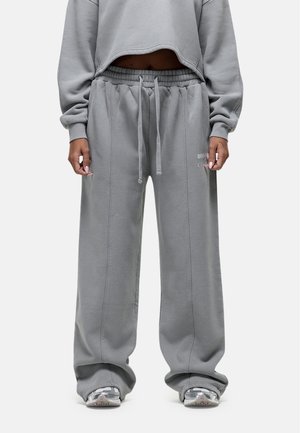 Grijze cropped sweatshirt gecombineerd met losse grijze sweatpants. De stof lijkt zacht met een geborstelde textuur. De sweatpants hebben een elastische tailleband.