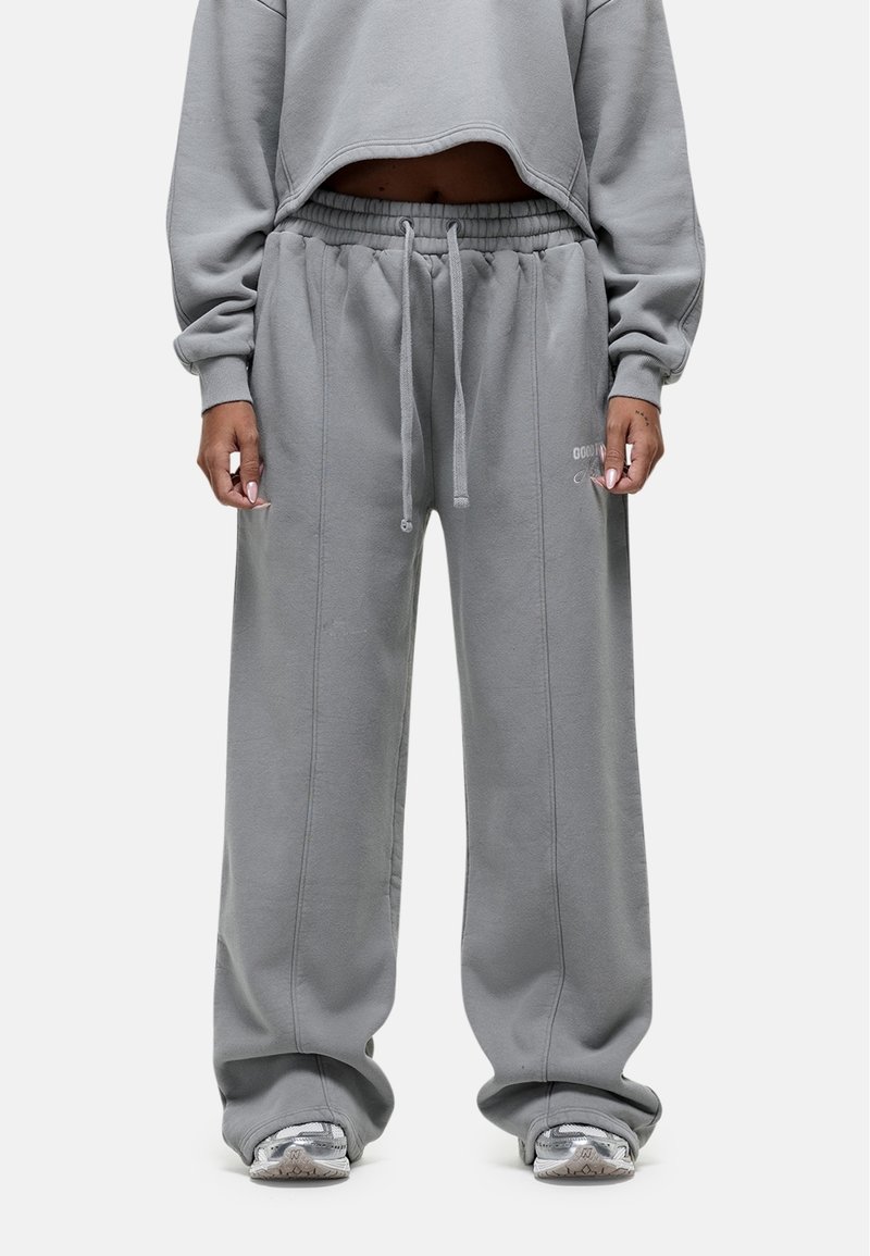 Grijze cropped sweatshirt gecombineerd met losse grijze sweatpants. De stof lijkt zacht met een geborstelde textuur. De sweatpants hebben een elastische tailleband.