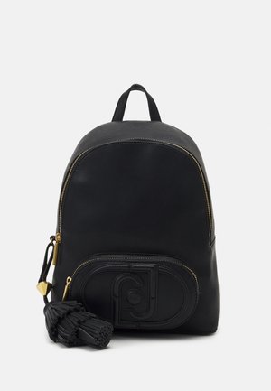 Sac à dos en cuir noir avec des fermetures éclair dorées, une poche avant embossée d'un logo et un porte-clés à pampille noire attaché sur le côté.