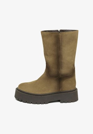 Bruine suède mid-calf laars met dikke donkerbruine profielzool en afgeronde neus, zijaanzicht op een witte achtergrond.