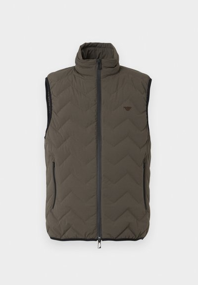 Αμάνικο, σκουρόχρωμο ελαιδί μπουφάν με ραφές, ψηλό γιακά, φερμουάρ μπροστά, πλαϊνές τσέπες με φερμουάρ και μικρό λογότυπο στο στήθος.