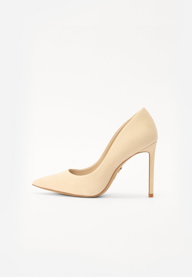 Beige korkokenkä, joka on valmistettu sileästä nahasta, jossa on teräväkärkinen muoto ja korkea stiletto-korko. Yksinkertainen muotoilu, jossa on sulavalinjainen siluetti.