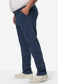 Tmavě modré džíny s rovný fit, vybavené bočními kapsami a klasickým designem poutek na opasek, doplněné světle zbarvenými teniskami.