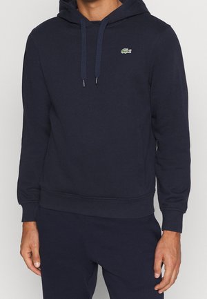 Felpa con cappuccio blu navy in misto cotone, con orlo e polsini a coste, tasca a marsupio e piccolo logo Lacoste verde sul petto.