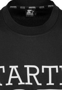 Crna mrežasta atletska majica s okruglim izrezom i istaknutim bijelim natpisom "STARTER" na prednjoj strani. Oznaka glasi "STARTER BLACK LABEL."