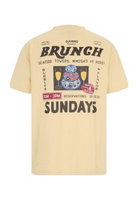 Beesinine T-särk graafilise tekstiga, mis reklaamib brunchi, mereandide torne, mimosasid ja broneeringuid pühapäeviti kell 10-15, koos jookide ja toidu illustreerimisega.