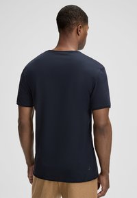 T-shirt a maniche corte di colore blu navy, realizzata in tessuto morbido, con collo tondo e vestibilità slim. La vista posteriore mostra una texture liscia e dettagli minimi.