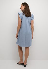 Světle modré šaty ve stylu džínoviny s volánkovými rukávy, po kolena, zaoblený lem a uvolněný střih. Hladký povrch a jednoduchý design.