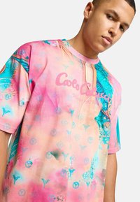 Farverig oversized t-shirt med et pink og blå abstrakt mønster, rund hals, korte ærmer og et logo-print på forsiden.