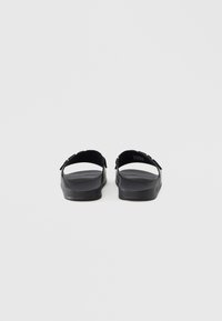 Mustad platvorm-sandaalid avatud kontsaga ja laia rihmaga, valmistatud siledast materjalist. Põhjaks on lame tald, millel on lihtne, minimalistlik disain.