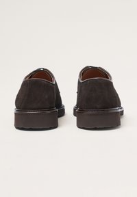 Dunkelbraune Wildlederschuhe mit runder Spitze, niedrigem Absatz und minimaler Naht. Das Innere hat ein kontrastierendes braunes Futter.