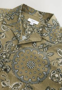 Zöld, mintás ing, amelyen navy kék és fehér paisley minta található. Ügyesített gallérral és gombos részletezéssel. A márkajelzés látható.