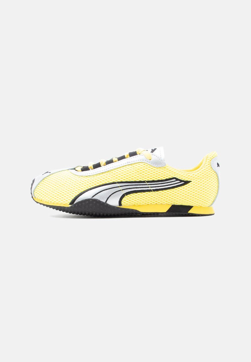 Baskets légères jaune et noir avec dessus en mesh, détail de logo blanc et noir, et semelle profilée basse, vues de côté.