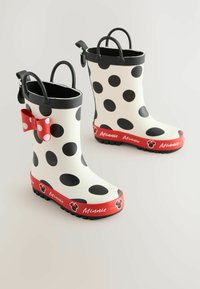 Weiße Gummistiefel mit großen schwarzen Punkten, roten Akzenten und einer roten Schleife. Der Text "Minnie" befindet sich am unteren Rand. Strukturierte schwarze Sohle.