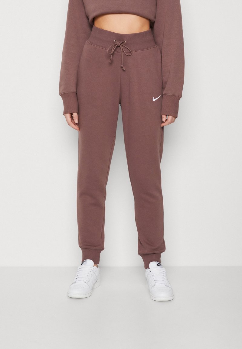Brown high-waist sweatpants with drawstring and cuffed ankles worn with white Nike sneakers and matching cropped sweatshirt.