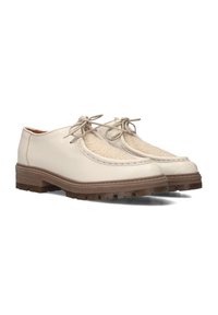 Beige leren schoenen met een gemêleerd stoffen paneel, ronde neus, veters en een dikke bruine rubberen zool met ribbelpatronen.