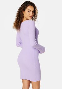 Abito a maglia a coste in lavanda chiaro con maniche lunghe e una silhouette aderente, caratterizzato da un orlo scallop e un tessuto testurizzato.