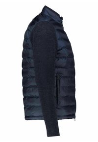 Navy blue puffer vest with a high collar and zippered pocket, paired with dark, textured long sleeves. Smooth, quilted fabric detailing.