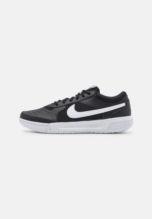 Black low-top sneaker with white Nike swoosh, black laces, and white sole with speckled detail, shown in side profile on white background.