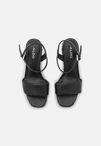 Paire de sandales noires Aldo avec bout carré, large bride avant et boucles réglables à la cheville, vue de dessus sur fond blanc.