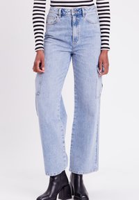 Hoge taille, licht gewassen, wijde jeans met zijzakken en een knopenrits, voorzien van een schone afwerking en minimale vervaging.