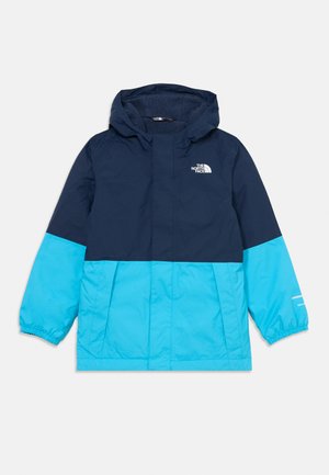 Blå og marineblå hettegenser med elastiske mansjetter, glidelås foran, og The North Face-logoen på øvre venstre side. Holdbart, lett materiale.