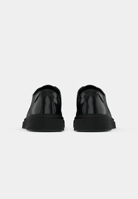 Sorte lædersko med en blank overflade, rund tå og struktureret gummisål. Minimalistisk design uden synlige materialer eller dekorationer.