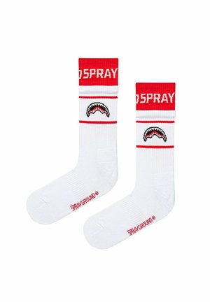 Calzini bianchi con bande rosse in alto, con testo "SPRAY", grafica della bocca di uno squalo sul polpaccio e testo "SPRAYGROUND" vicino alle dita dei piedi.