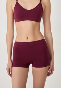 Bralette bordeaux avec des fines bretelles et un shorty assorti. Textile lisse et doux avec un design simple et épuré sans motifs visibles.