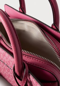 Τσάντα χειρός φούξια με υφή, με φερμουάρ, διπλές κορυφαίες λαβές και αντίθετη εσωτερική επένδυση. Η εσωτερική επένδυση είναι από λείο μπεζ ύφασμα.