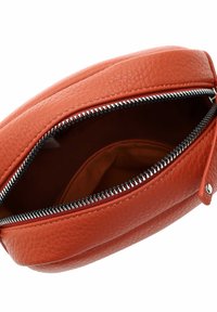 Väike tekstuuriga oranž nahast kott, millel on osaliselt avatud musta ja hõbedase lukuga, näidates tühja sisemust ja kangast voodrit.