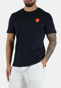 T-shirt a maniche corte di colore blu navy in un tessuto morbido, con un logo rosso sul petto e un piccolo etichetta sulla manica. Design slim fit.