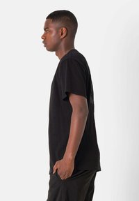 Zwarte katoenen T-shirt met korte mouwen, een relaxte pasvorm en een ronde halslijn. Details omvatten een grafische print op de achterkant.