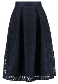 Námořnická midi sukně s přiléhavým pasem, která má texturovaný vzor včelí plástve a výřezové detaily podél lemu.
