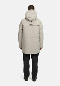 Gaišpelēka kapuces parka ar taisnu piegriezumu, ietverot aizmugurējo daļu, smalku diegu šuvēm un melnas krāsas akcentu netālu no kapuces.