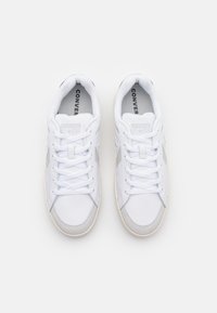 White sneakers with gray accents, featuring a smooth leather upper, round toe, lace-up closure, and a rubber sole.