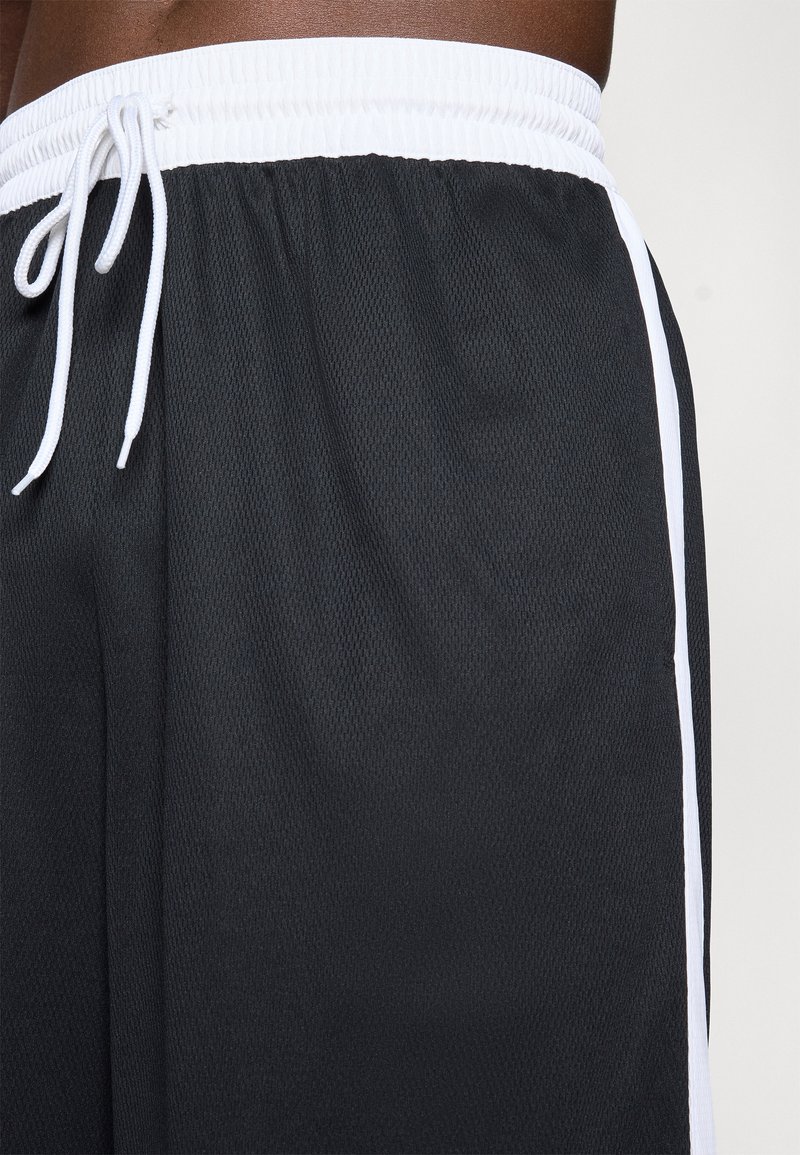 Pantalones cortos deportivos negros hechos de un material de malla transpirable, con una cinturilla elástica blanca y franjas laterales blancas, y un cierre con cordón.