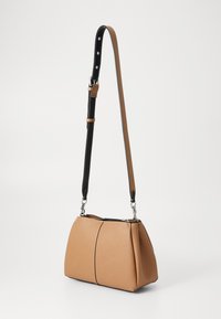 Tan leather handbag with a textured finish, black detachable strap, and silver hardware. Rounded shape with a zipper closure at the top.