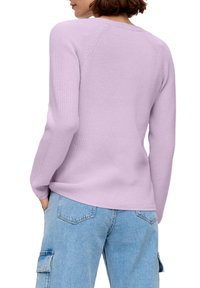 Pull en tricot violet clair à manches longues, texture côtelée, coupe décontractée, assorti à un jean cargo bleu délavé.