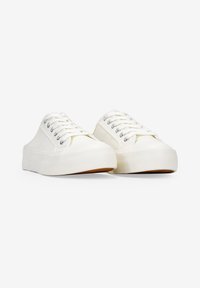 Sneakers bianchi in tela con un design a profilo basso, chiusura con lacci, occhielli argentati e suole in gomma testurizzata. Finitura liscia e forma arrotondata.